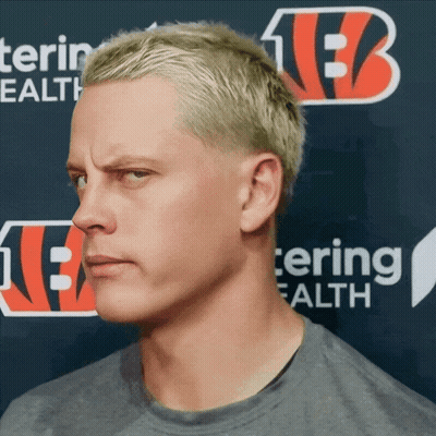 A Man With Blonde Hair Stands In Front Of A Sign That Says Tering Health GIF