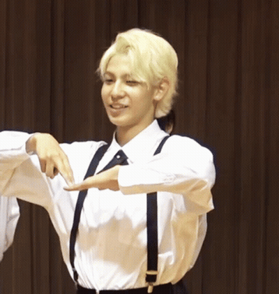 A Man With Blonde Hair Wearing Suspenders And A White Shirt Smiles GIF