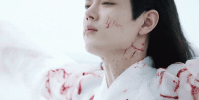 A Man With Blood On His Face And Neck Is Wearing A White Robe . GIF