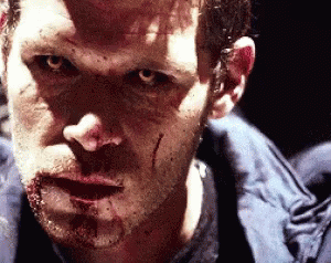 A Man With Blood On His Face Is Looking At The Camera GIF