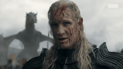 A Man With Blood On His Face Stands In Front Of A Dragon With Hbo Written On The Bottom Right GIF
