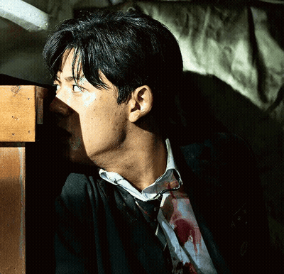 A Man With Blood On His Shirt Is Standing Next To A Table GIF