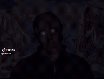 A Man With Blue Eyes Is Standing In Front Of A Painting With A Star Of David In The Background GIF