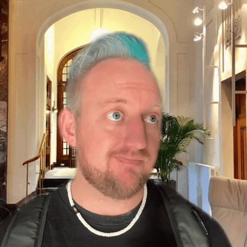 A Man With Blue Hair And A Beard Is Looking At The Camera GIF