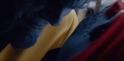 A Man With Blue Hair And A Woman With Red Hair Are Standing Next To Each Other . GIF