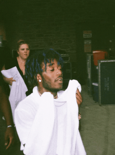 A Man With Blue Hair Is Holding A White Shirt GIF