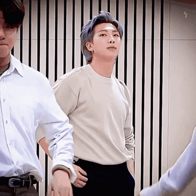A Man With Blue Hair Is Standing Next To Another Man In A White Shirt And Black Pants . GIF