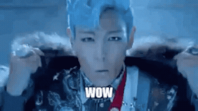 A Man With Blue Hair Is Wearing A Fur Coat And Holding A Microphone . GIF