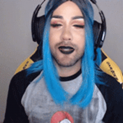 A Man With Blue Hair Is Wearing Headphones And A Wig While Sitting In A Chair . GIF