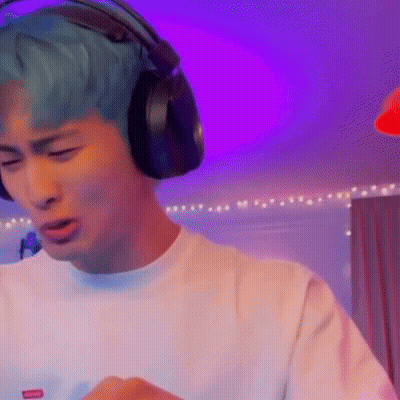 A Man With Blue Hair Is Wearing Headphones While Playing A Video Game . GIF