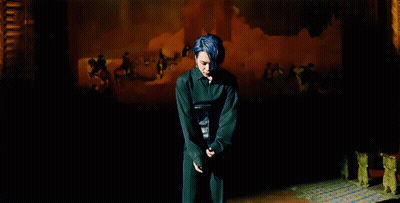 A Man With Blue Hair Stands In Front Of A Painting That Says ' A ' On It GIF