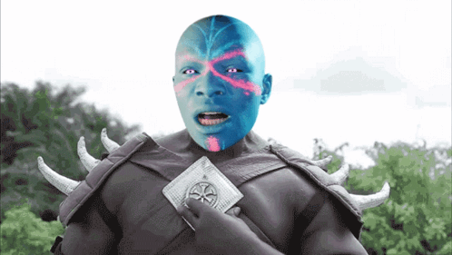 A Man With Blue Paint On His Face Is Holding A Wallet GIF