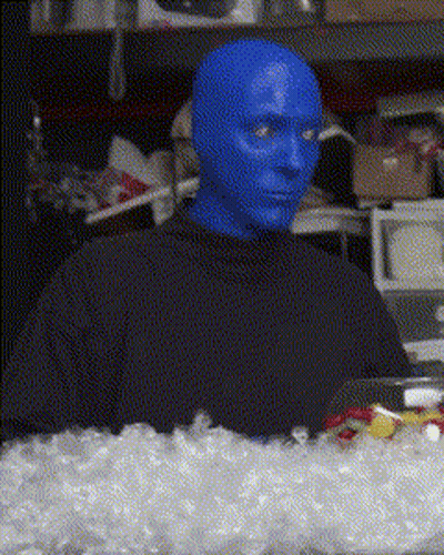 A Man With Blue Paint On His Face Is Sitting In Front Of A Pile Of Ice GIF