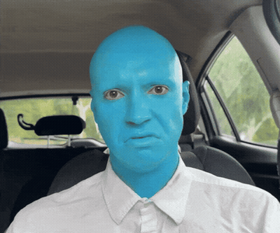 A Man With Blue Paint On His Face Is Sitting In The Driver 'S Seat Of A Car GIF