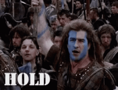 A Man With Blue Paint On His Face Is Standing In A Crowd . GIF