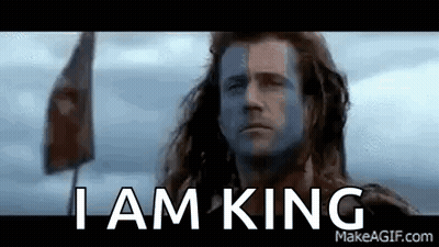 A Man With Blue Paint On His Face Is Standing In Front Of A Flag . GIF