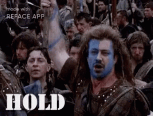 A Man With Blue Paint On His Face Is Surrounded By A Crowd Of People . GIF