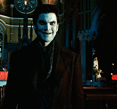 A Man With Blue Paint On His Face Stands In Front Of A Building GIF