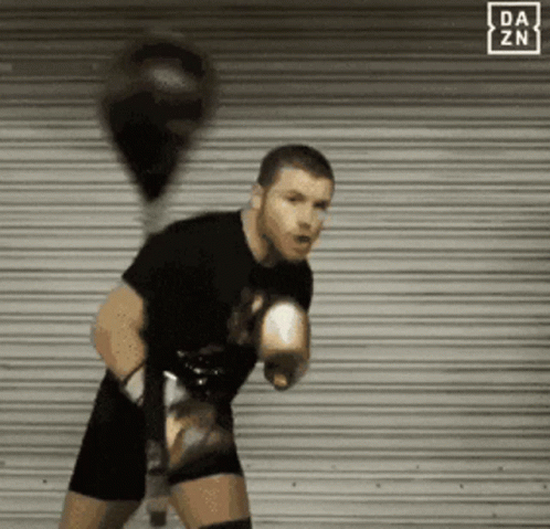 A Man With Boxing Gloves Is Standing In Front Of A Da Zn Sign GIF