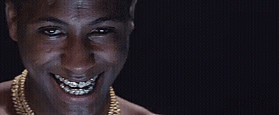 A Man With Braces On His Teeth Is Smiling And Wearing A Gold Chain . GIF