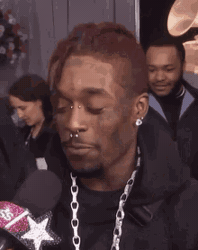A Man With Braces On His Teeth Is Smiling While Holding A Microphone . GIF