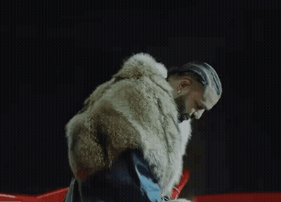 A Man With Braids Is Wearing A Fur Coat And A Blue Jacket . GIF