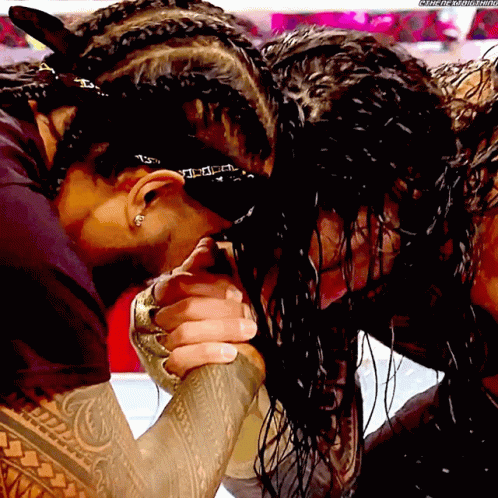 A Man With Braids On His Head Holds Another Man 'S Hand In A Wrestling Ring GIF