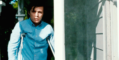 A Man With Crutches Is Standing In Front Of A Door GIF