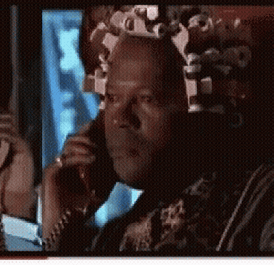 A Man With Curlers In His Hair Is Talking On A Phone GIF