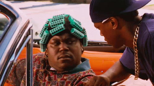 A Man With Curlers On His Head Is Sitting In A Car With Another Man . GIF