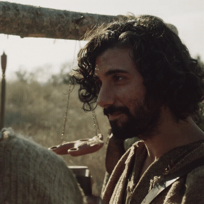 A Man With Curly Hair And A Beard Holds A Scale GIF