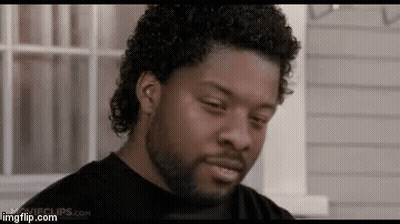 A Man With Curly Hair And A Beard Is Looking At The Camera . GIF