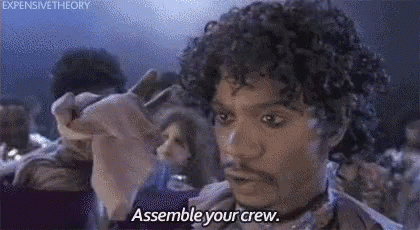 A Man With Curly Hair And A Beard Is Saying `` Assemble Your Crew '' While Holding A Piece Of Paper . GIF