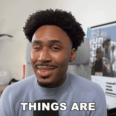 A Man With Curly Hair And A Beard Is Smiling And Says Things Are GIF