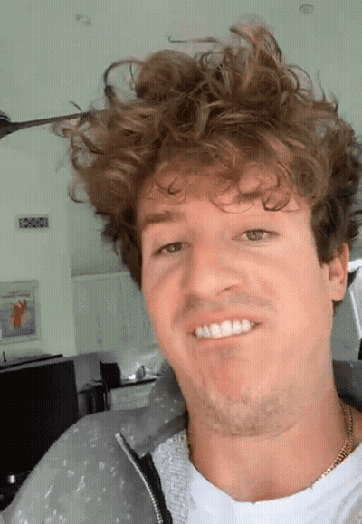 A Man With Curly Hair And A Beard Is Smiling GIF