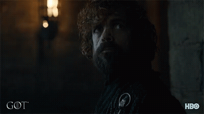 A Man With Curly Hair And A Beard Is Standing In A Dark Room With The Word Got On The Bottom Right GIF