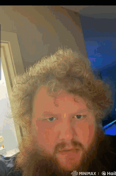 A Man With Curly Hair And A Beard Is Taking A Selfie In A Room GIF