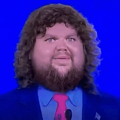 A Man With Curly Hair And A Beard Is Wearing A Pink Tie And A Blue Suit . GIF