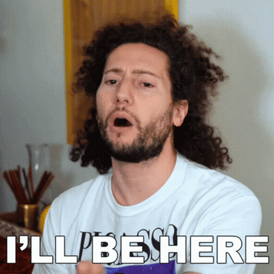 A Man With Curly Hair And A Beard Is Wearing A White Shirt That Says I 'Ll Be Here GIF