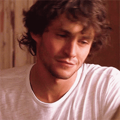 A Man With Curly Hair And A Beard Is Wearing A White Shirt GIF