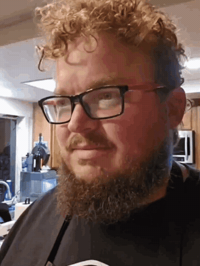 A Man With Curly Hair And A Beard Wearing Glasses And A Black Shirt GIF