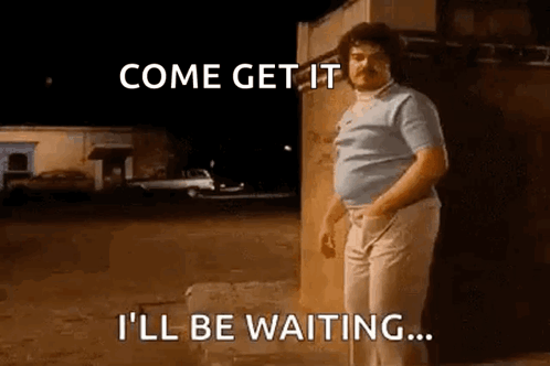 A Man With Curly Hair And A Mustache Is Standing In Front Of A Building . GIF