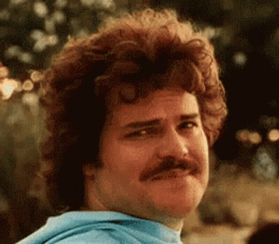 A Man With Curly Hair And A Mustache Is Wearing A Blue Hoodie And Making A Funny Face . GIF