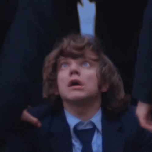 A Man With Curly Hair And Blue Eyes Looks Up At Something GIF