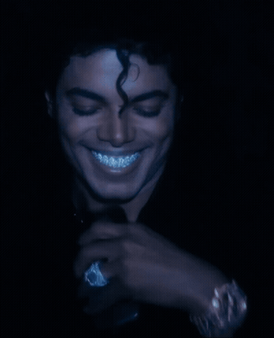 A Man With Curly Hair And Braces On His Teeth Is Smiling GIF