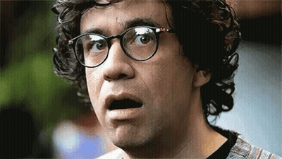 A Man With Curly Hair And Glasses Is Making A Funny Face . GIF