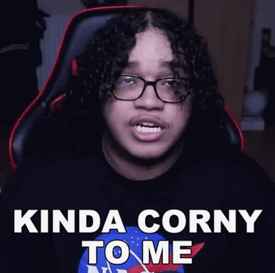 A Man With Curly Hair And Glasses Is Sitting In A Chair And Says Kinda Corny To Me GIF