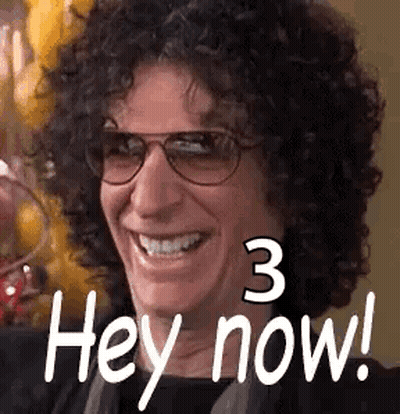 A Man With Curly Hair And Glasses Is Smiling And Saying Hey Now . GIF
