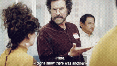A Man With Curly Hair And Glasses Is Talking To A Woman Who Says Here I Did N't Know There Was Another GIF