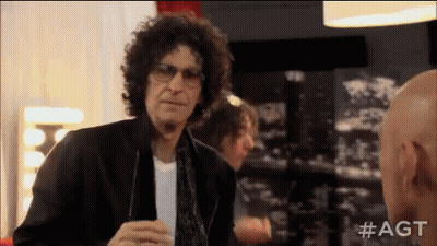 A Man With Curly Hair And Glasses Is Talking To Another Bald Man . GIF